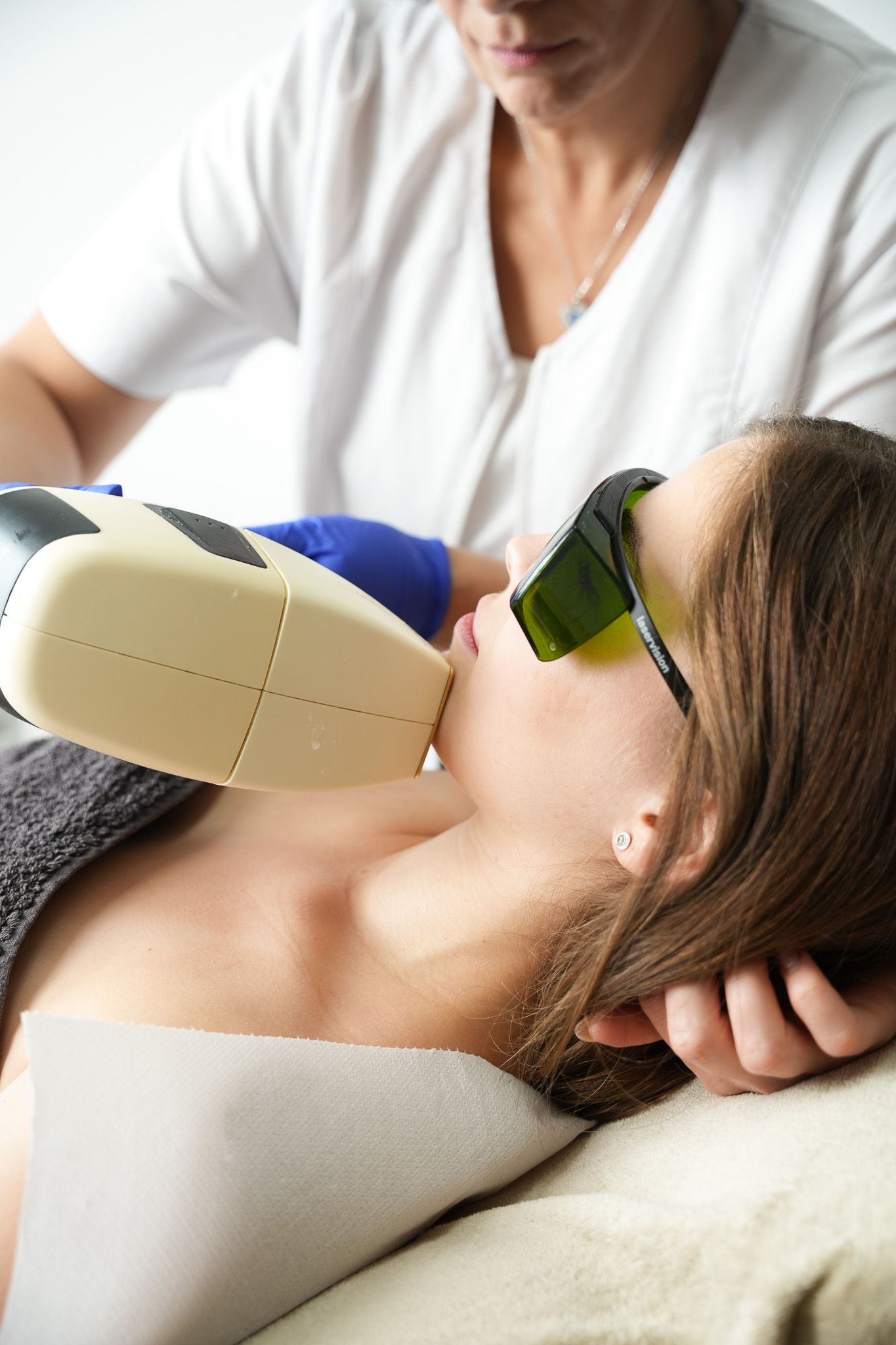 Eine Frau lässt sich in einer Klinik von einer Kosmetikerin die Haare am Kinn per Laser entfernen.