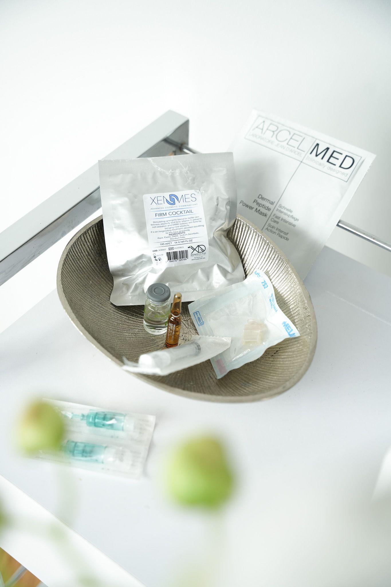 Medikamente in einer silbernen Schale auf einer weißen Oberfläche mit einem „PRISMED“-Papier und verschwommenem Grün.