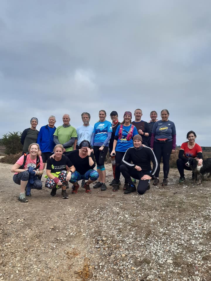 Group of people gathered outdoors on a cloudy day, some crouching and some standing.