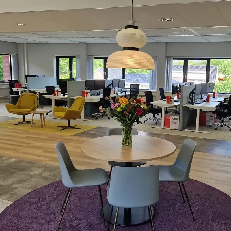 Een kantoor met een tafel en stoelen en een vaas met bloemen