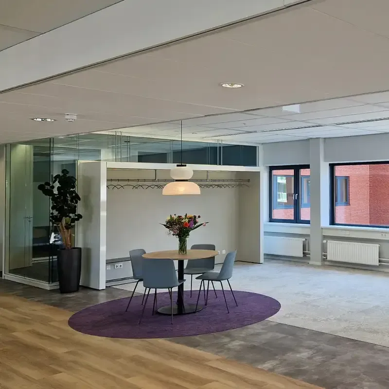 Een eetkamer met een tafel en stoelen en een paars tapijt