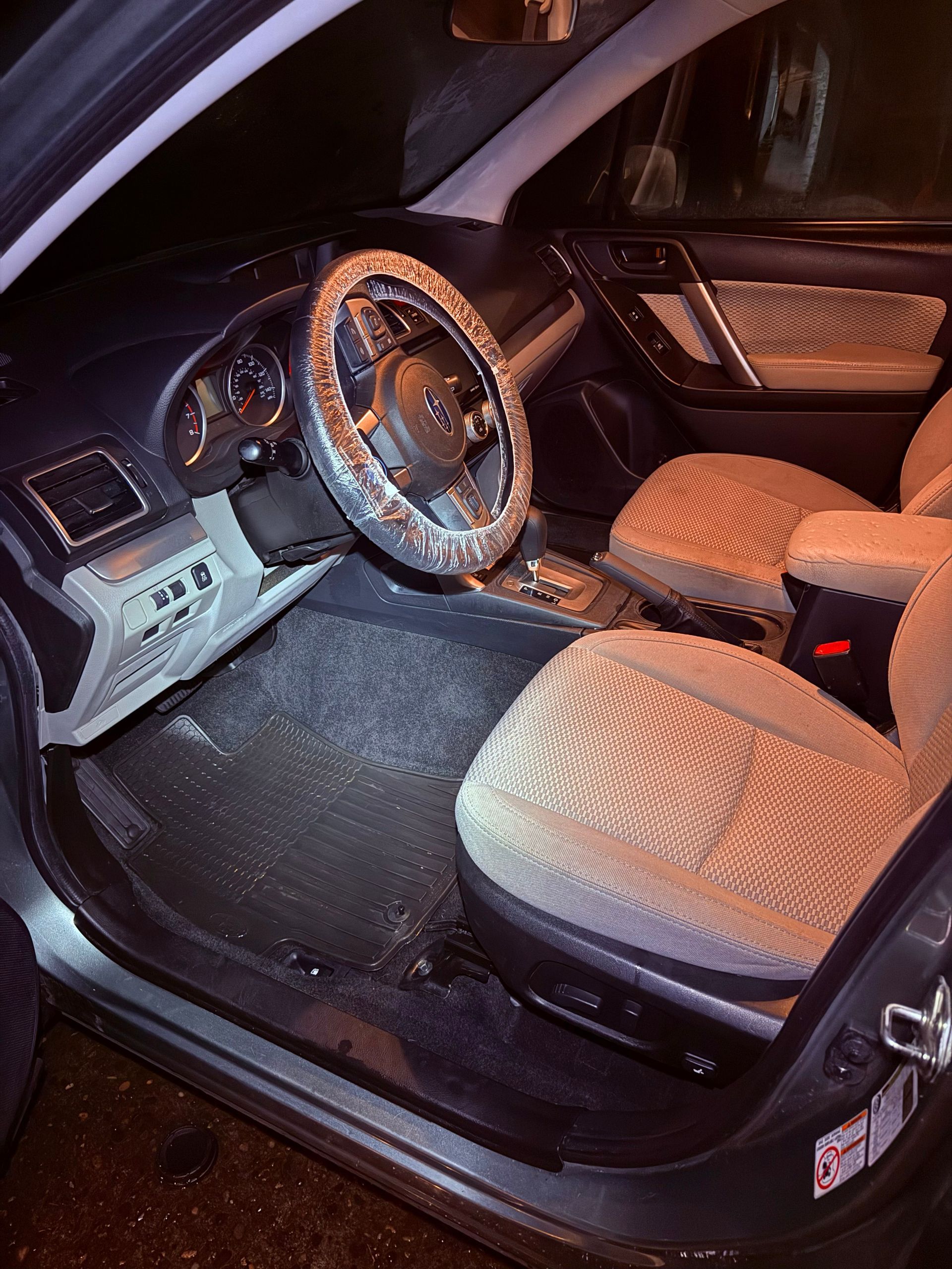 Car interior with tan seats, a black dashboard, and a steering wheel lit by warm light.