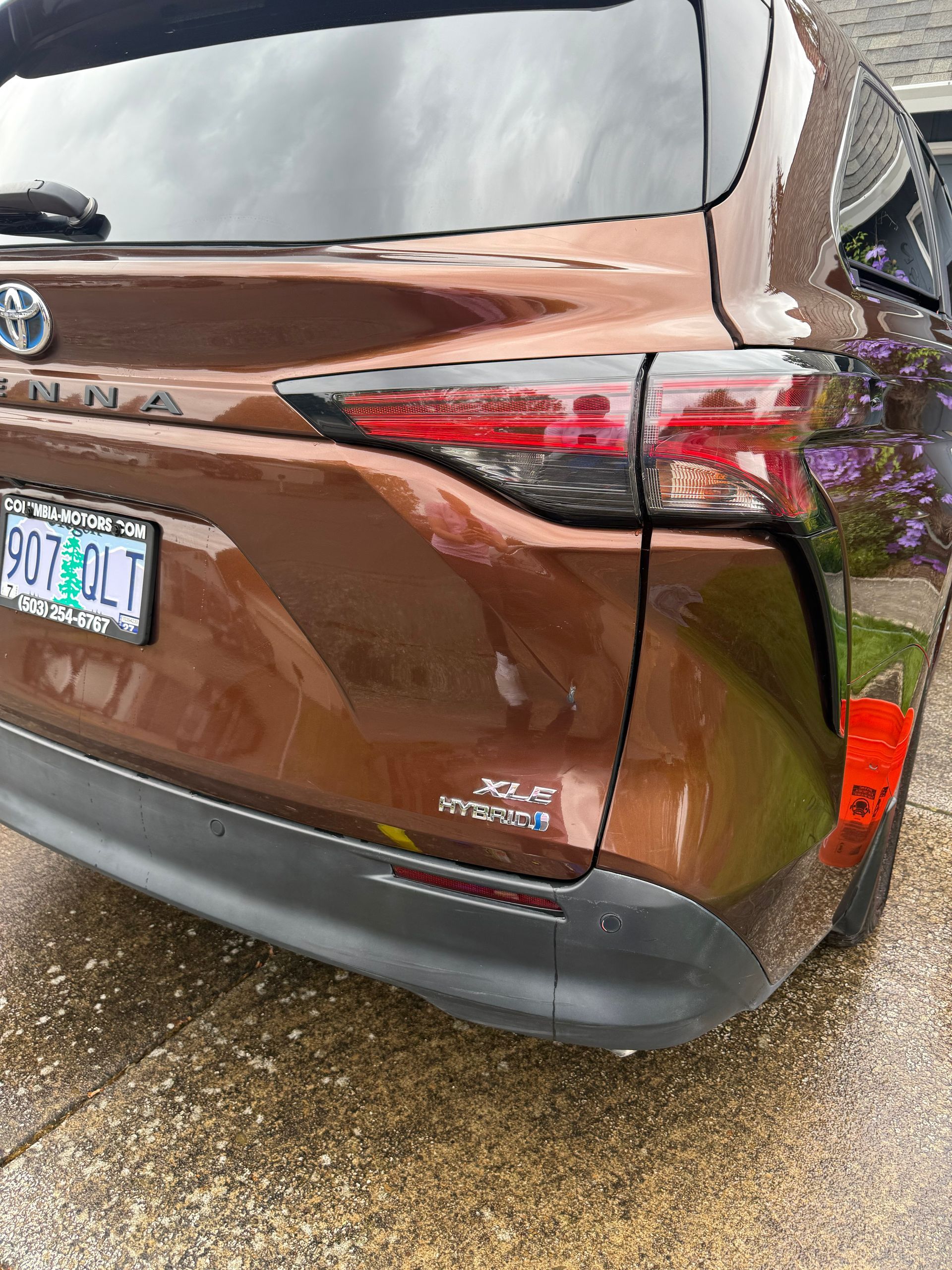 Rear view of a brown Toyota SUV with damage on the right side and a visible license plate.