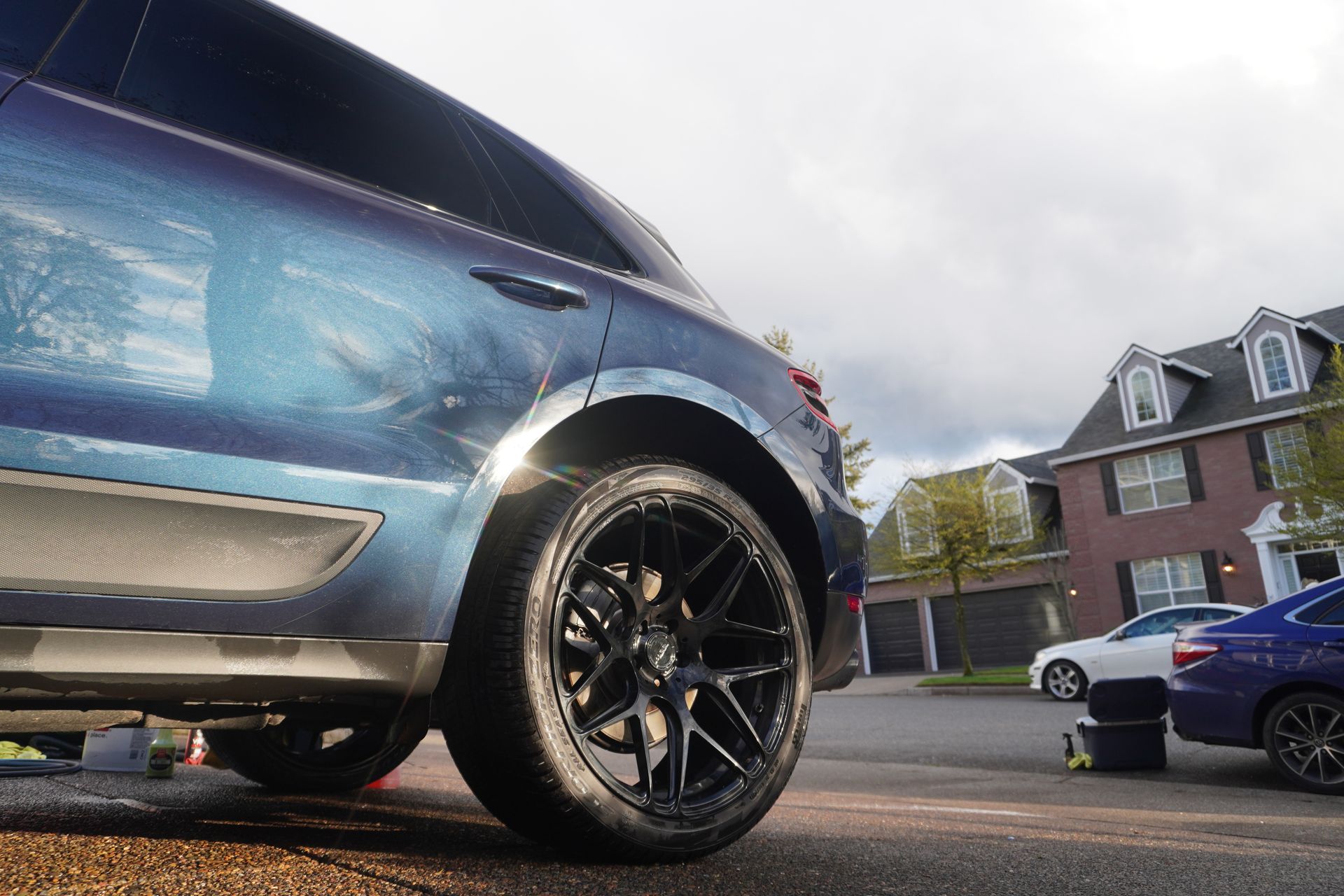 Blue SUV with black rims parked on a street in front of houses
