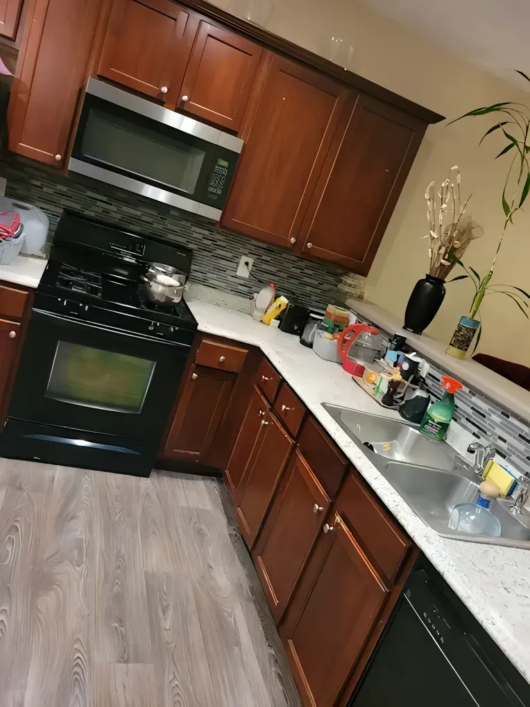 Kitchen with dark brown cabinets, black appliances, and light countertops.