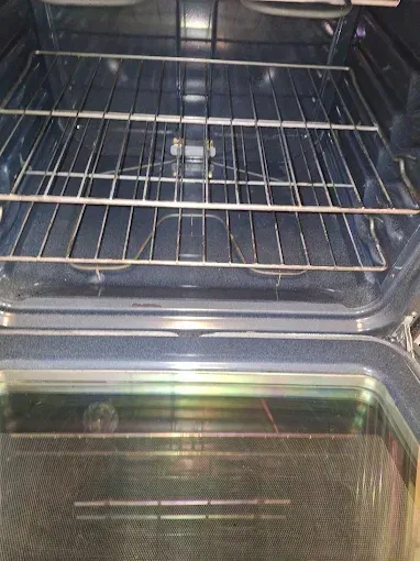 Inside of a clean oven with a top rack in place, bottom visible.