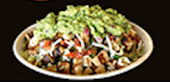 A bowl filled with a variety of ingredients, including guacamole, shredded cheese, and diced components.