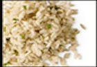 Close-up of cooked brown rice, speckled with small green herbs, on white background.