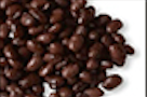 Pile of dark, glossy black beans, close-up view, scattered against a white edge.