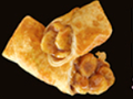 Two golden-brown egg rolls filled with a visible, brown, fruit filling, against a black background.