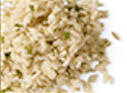 Close-up of cooked brown rice, speckled with small green herbs, on white background.