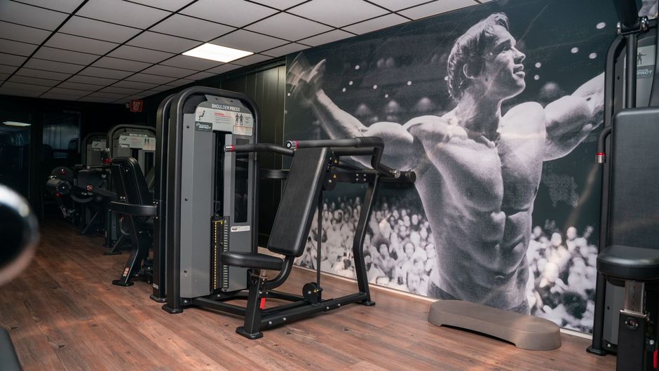 een sportschool met een foto van Arnold Schwarzenegger aan de muur.