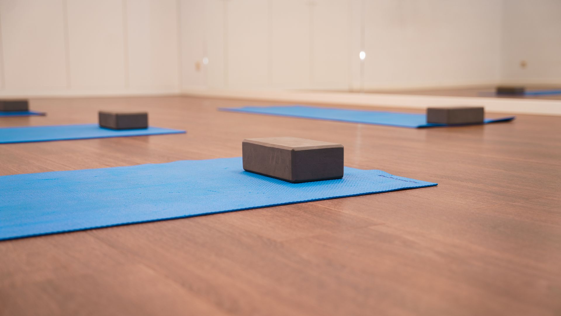Een groep blauwe yogamatten en yogablokken op een houten vloer.
