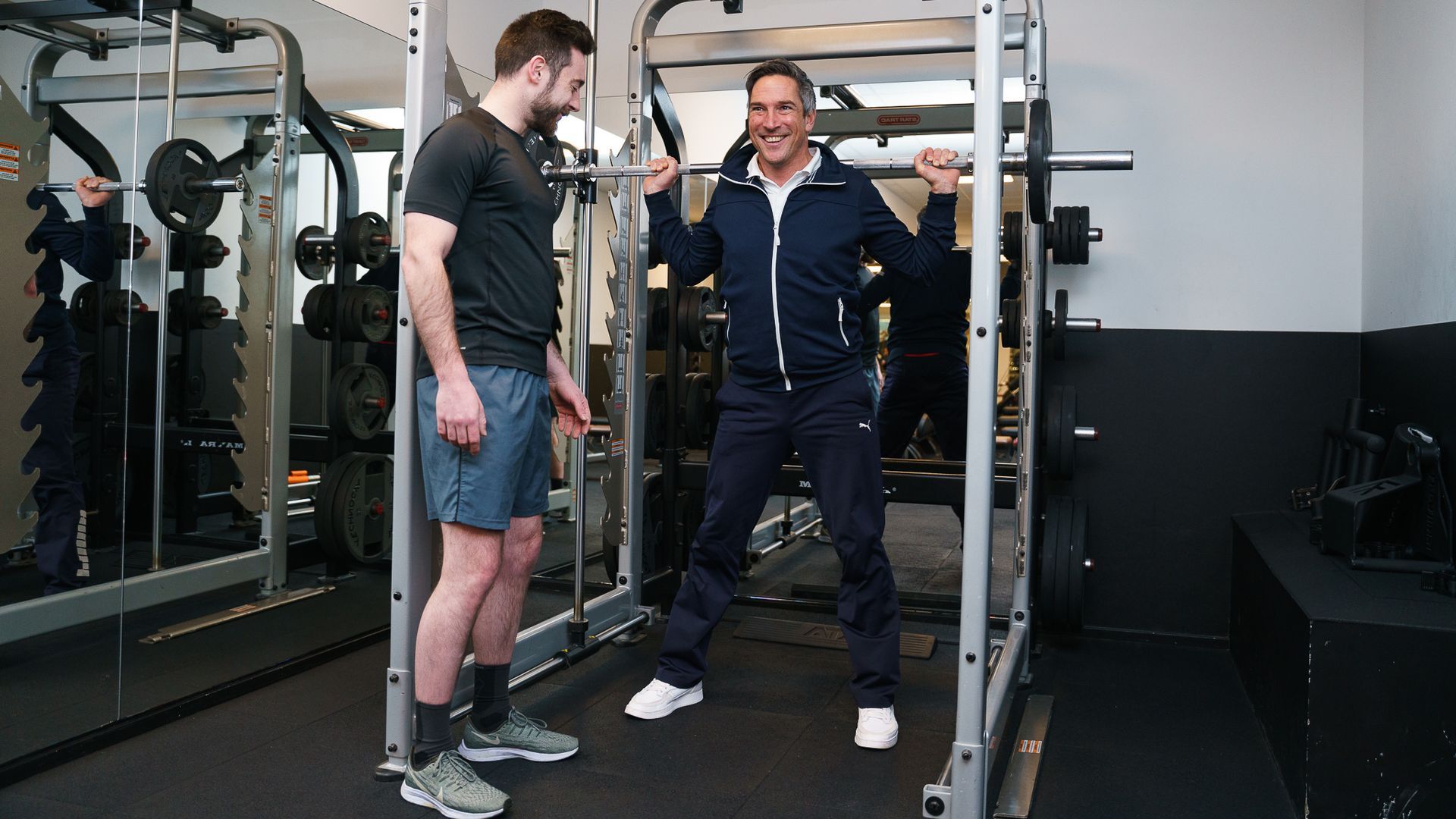 Twee mannen staan ​​naast elkaar in een sportschool.