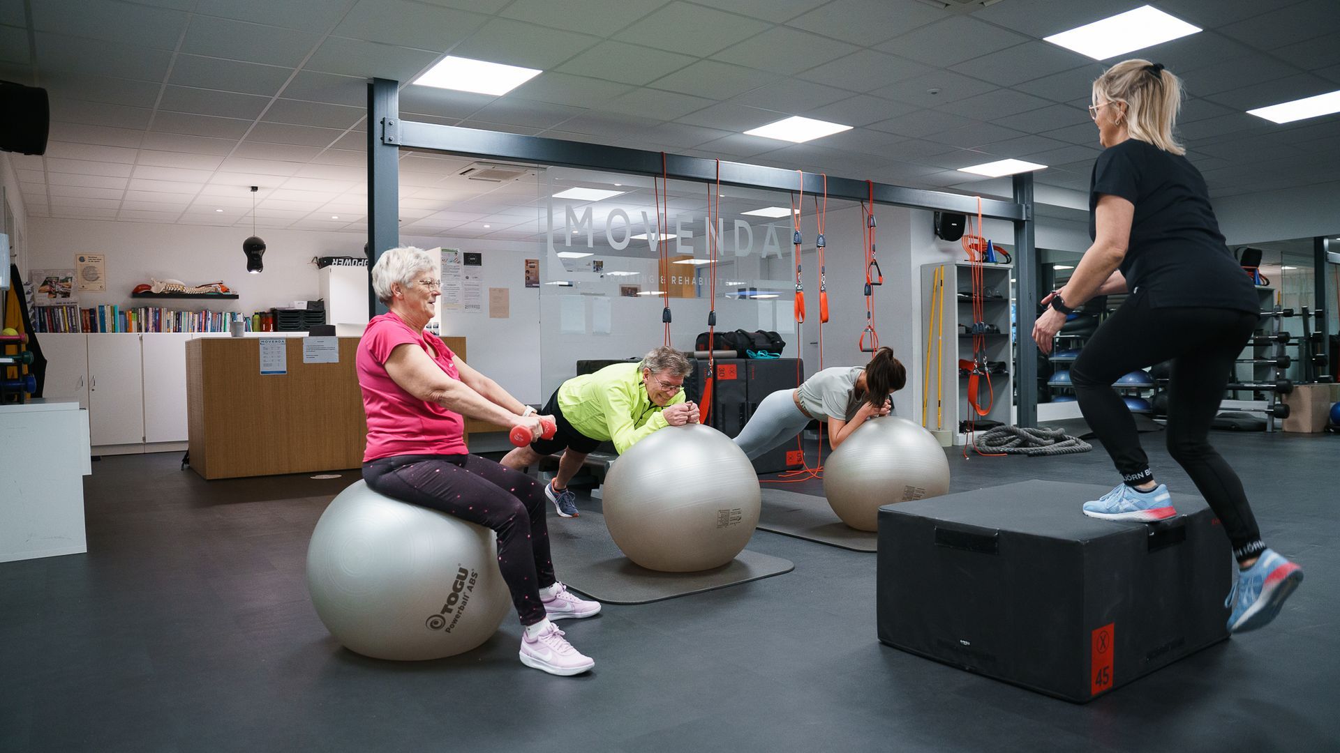Een groep mensen zit op oefenballen in een sportschool.