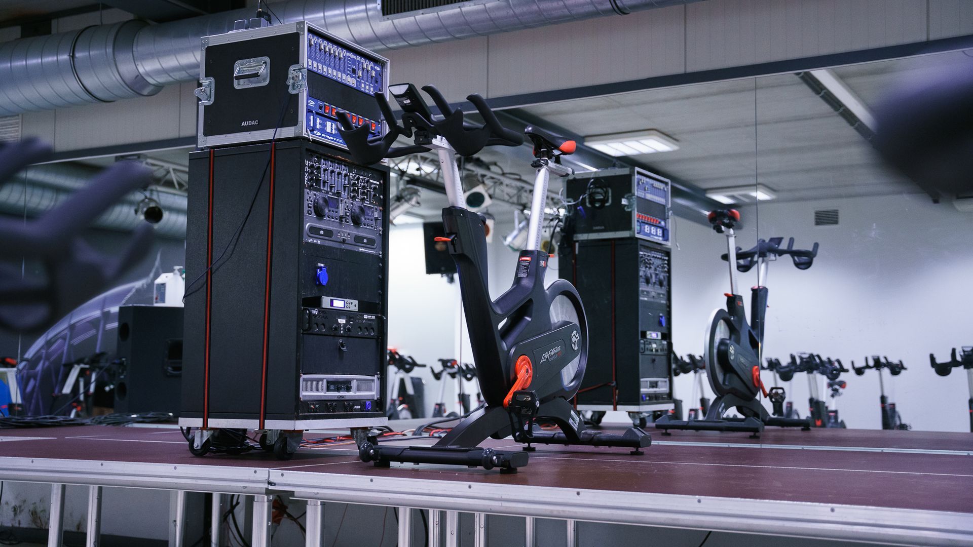 Een rij hometrainers staat op een podium in een sportschool.