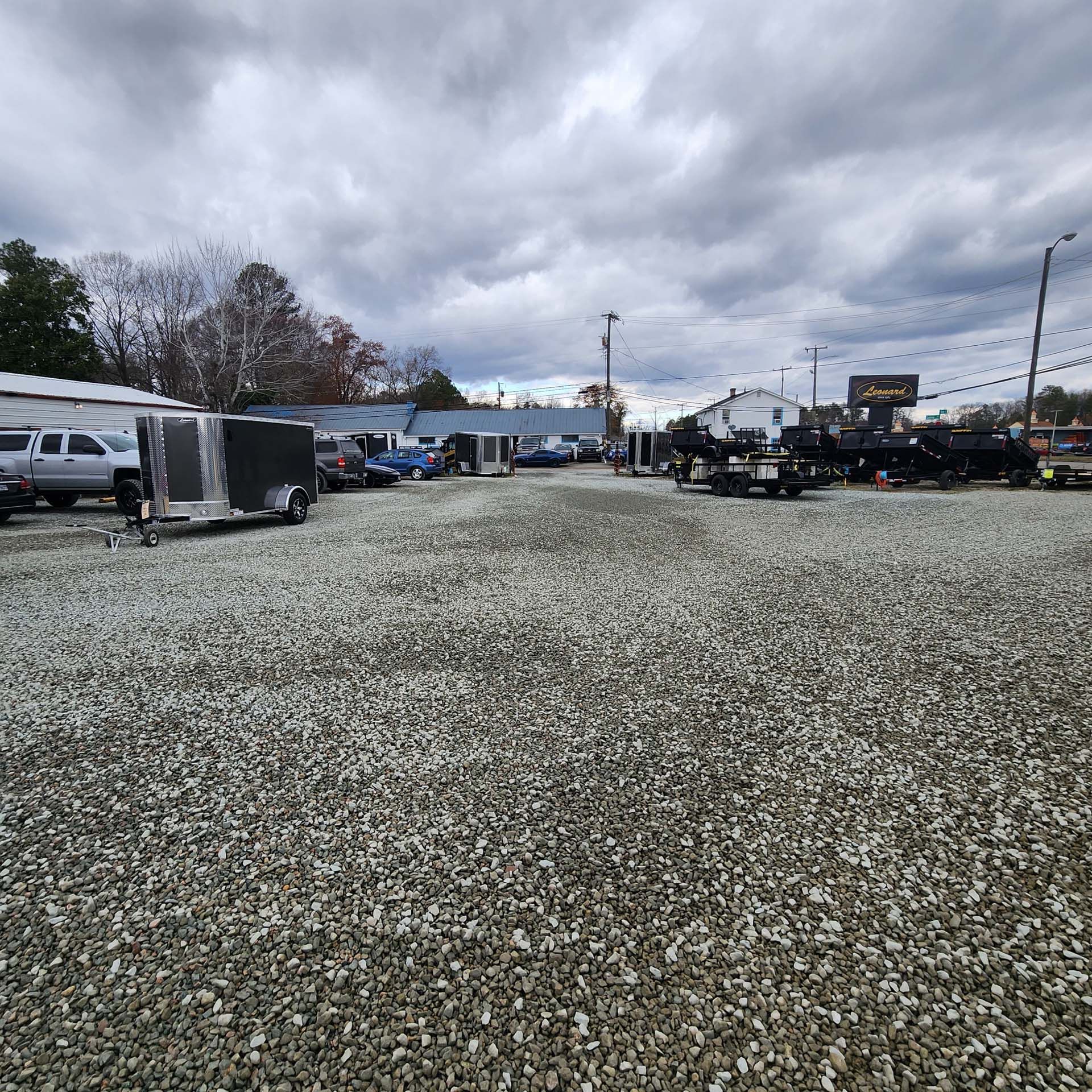 A lot of cars are parked in a gravel lot.