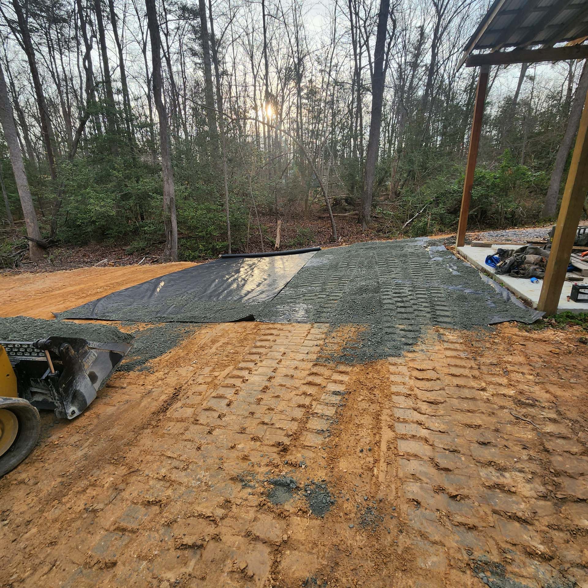 A bulldozer is working on a dirt road in the woods.