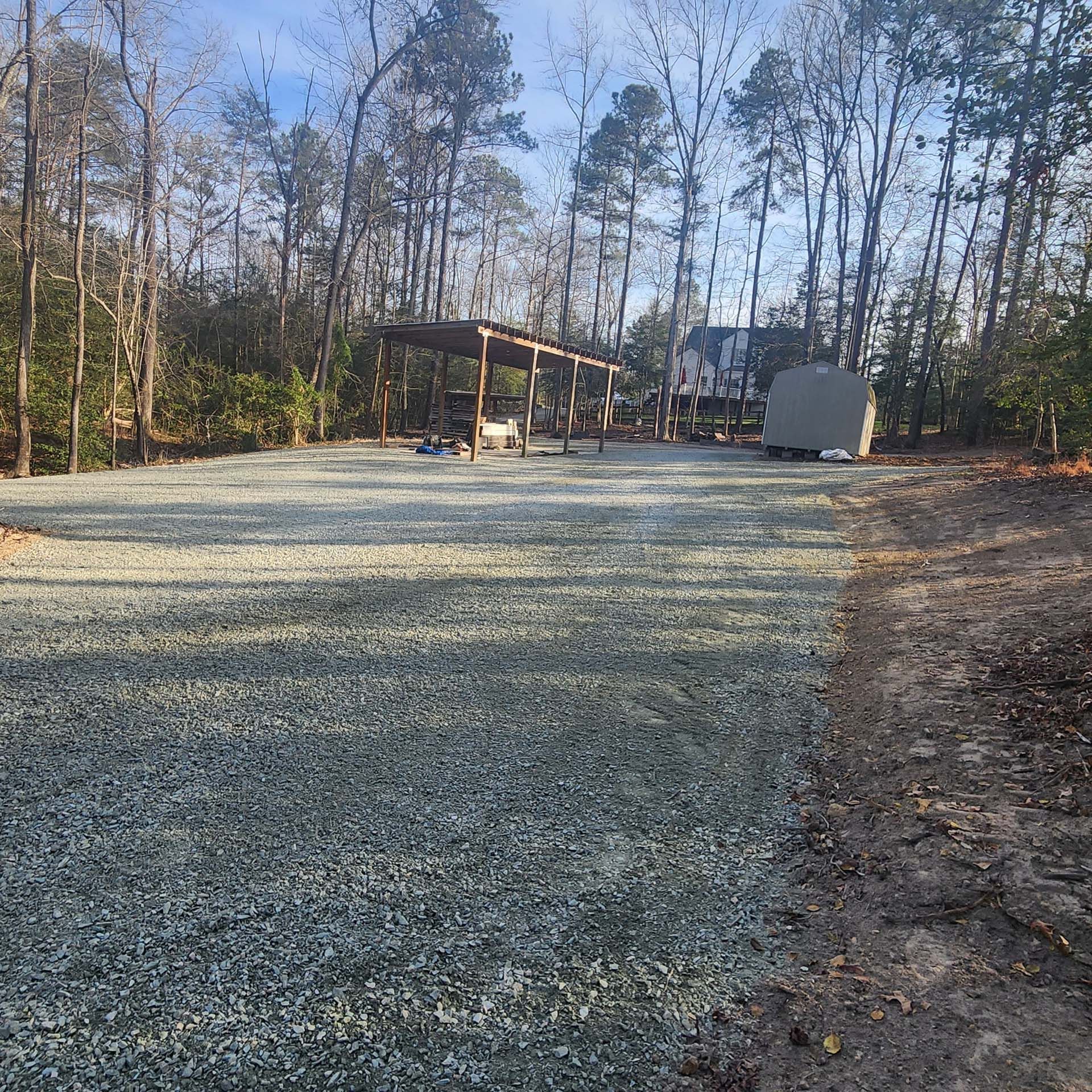 A gravel driveway leading to a house in the woods.