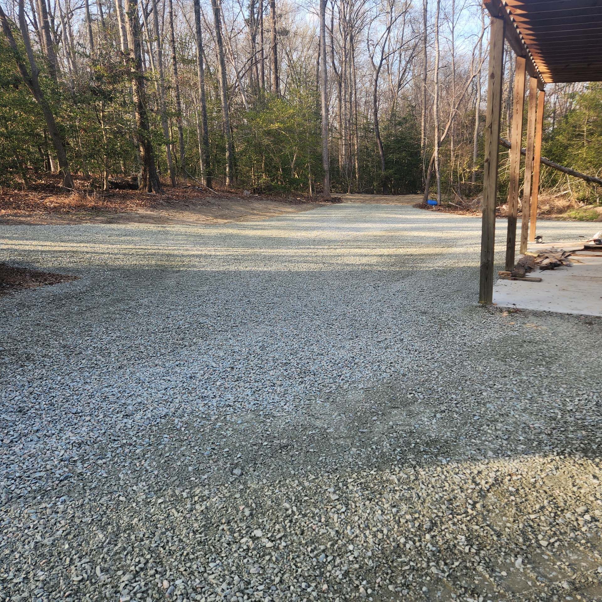 A gravel driveway with trees in the background