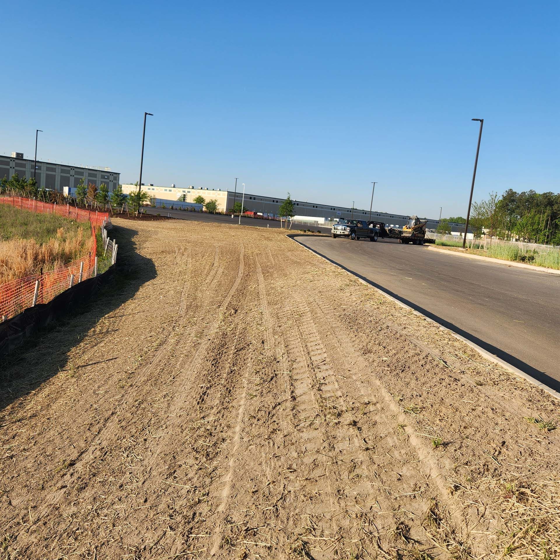 A truck is driving down a dirt road next to a building.