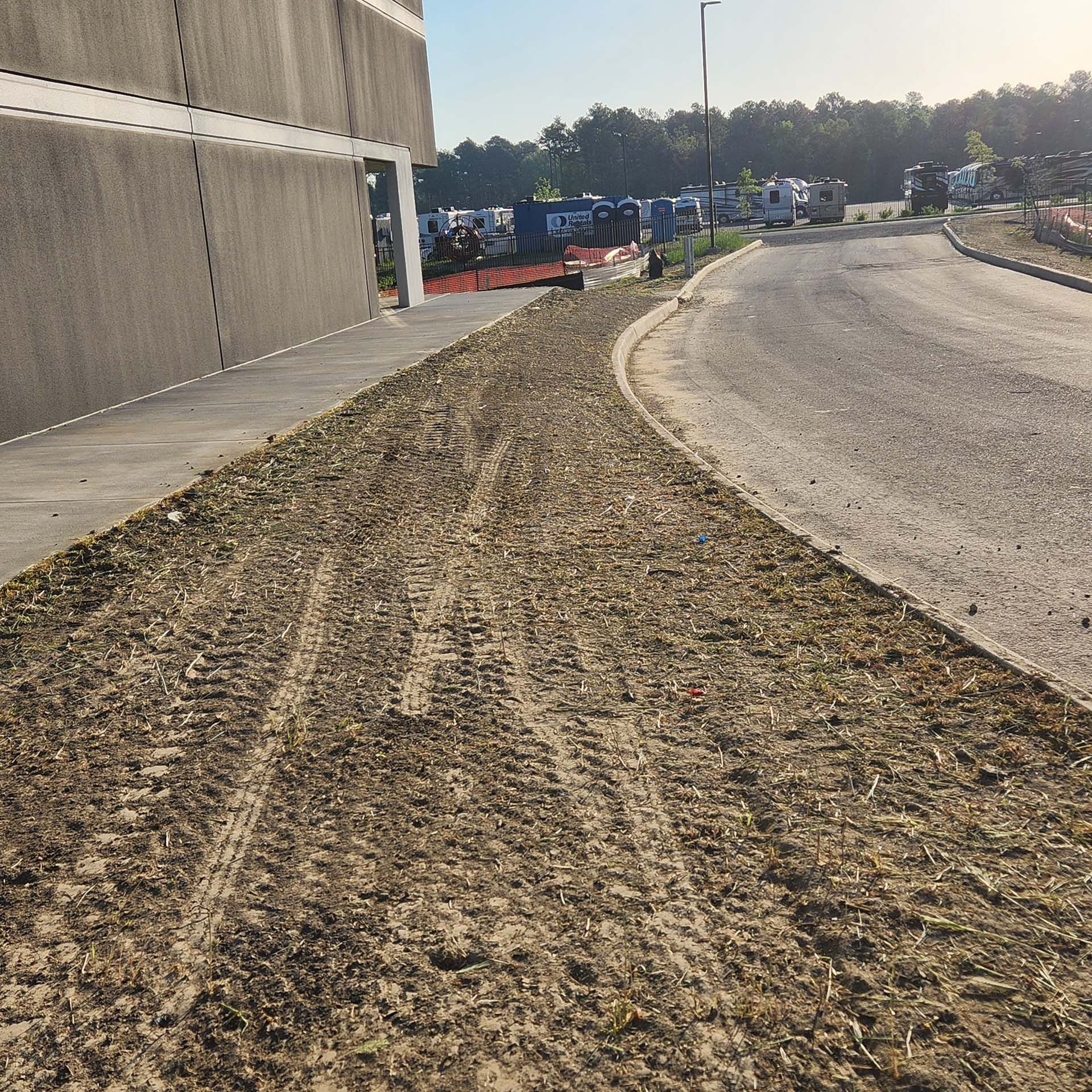 A dirt road with a concrete wall in the background