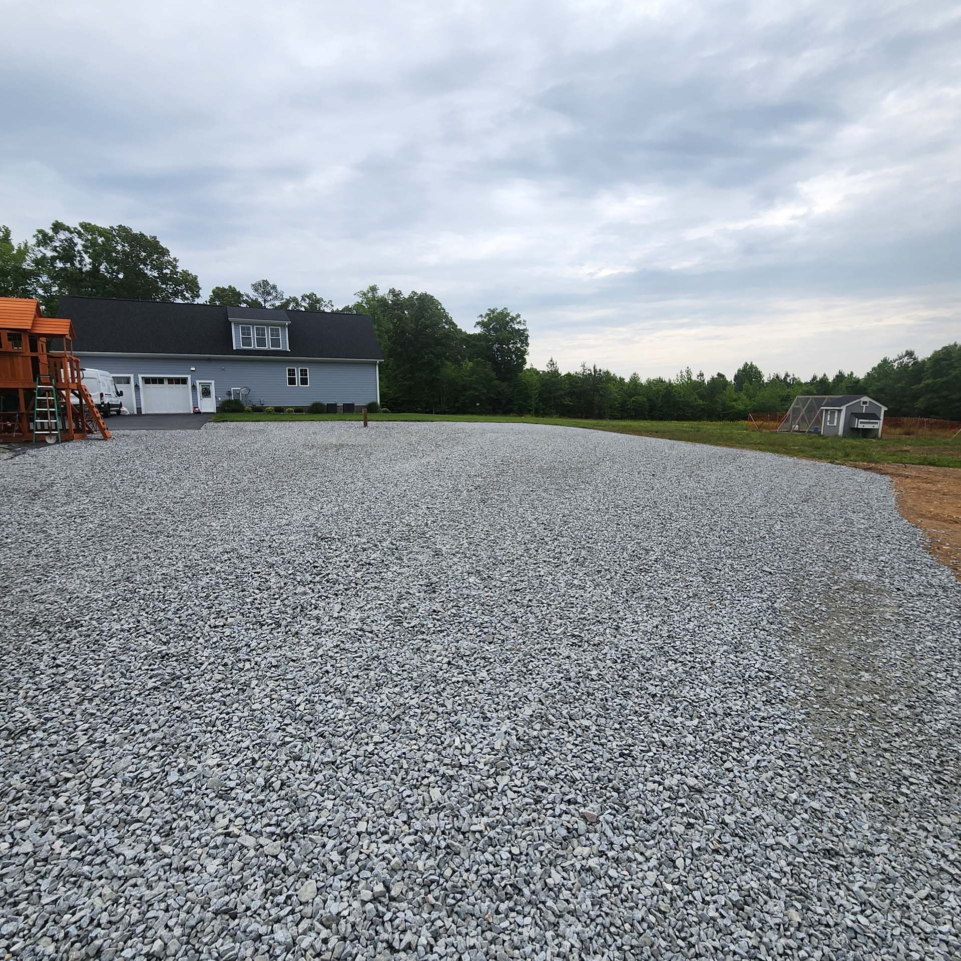 A gravel driveway with a house in the background
