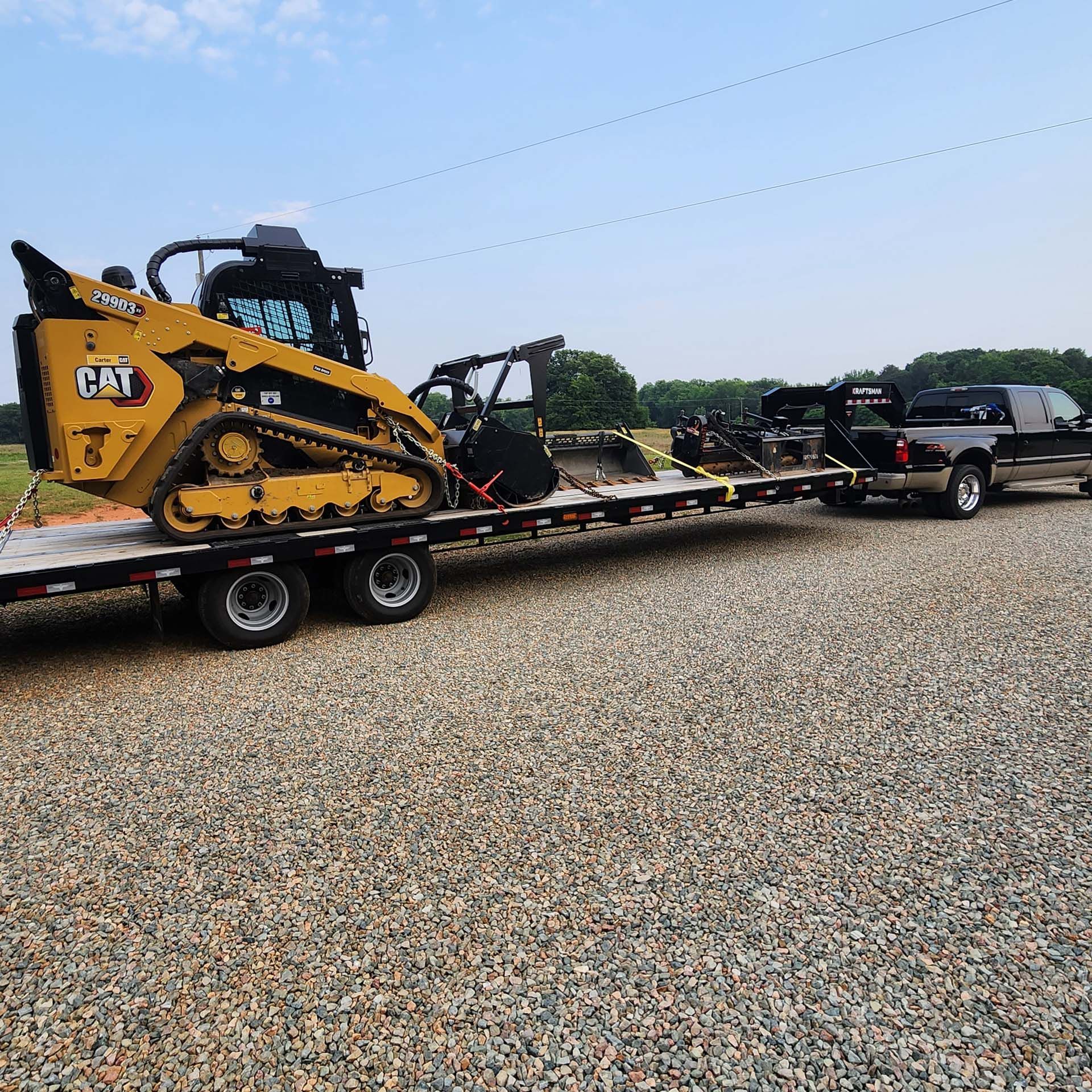 A cat tractor is being towed by a truck