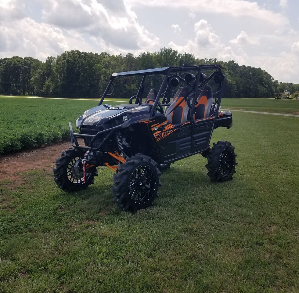 A black and orange atv is parked in a grassy field