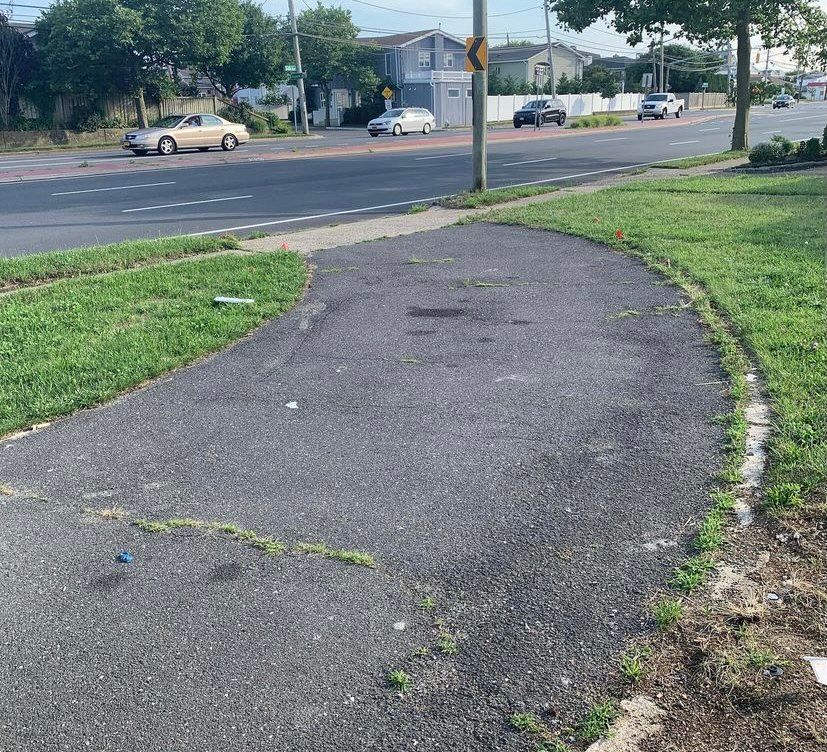 A car is driving down a street next to a sidewalk