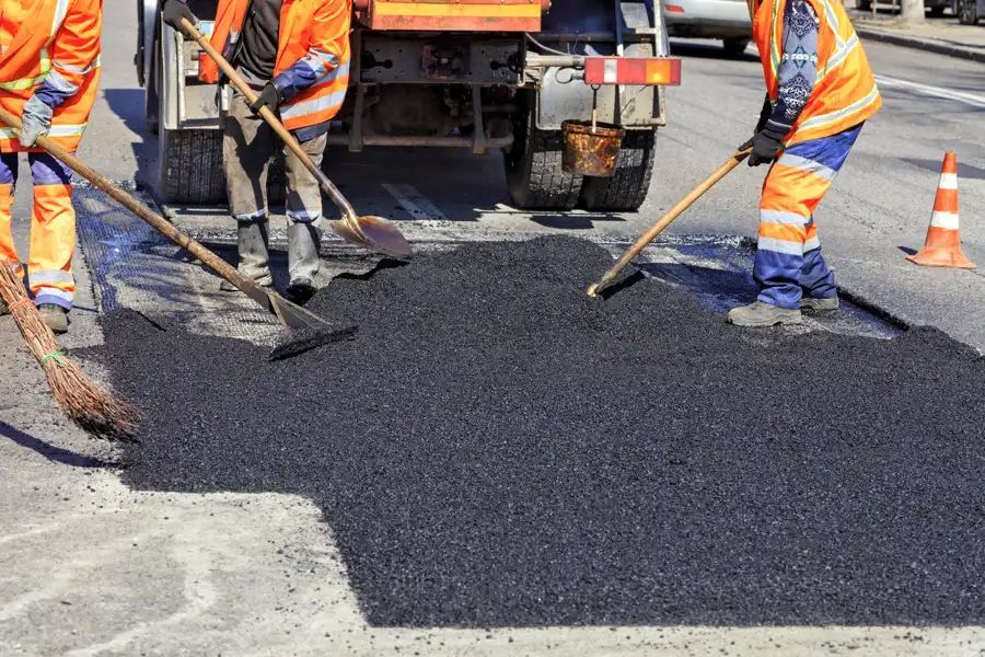 A group of construction workers are working on a road.