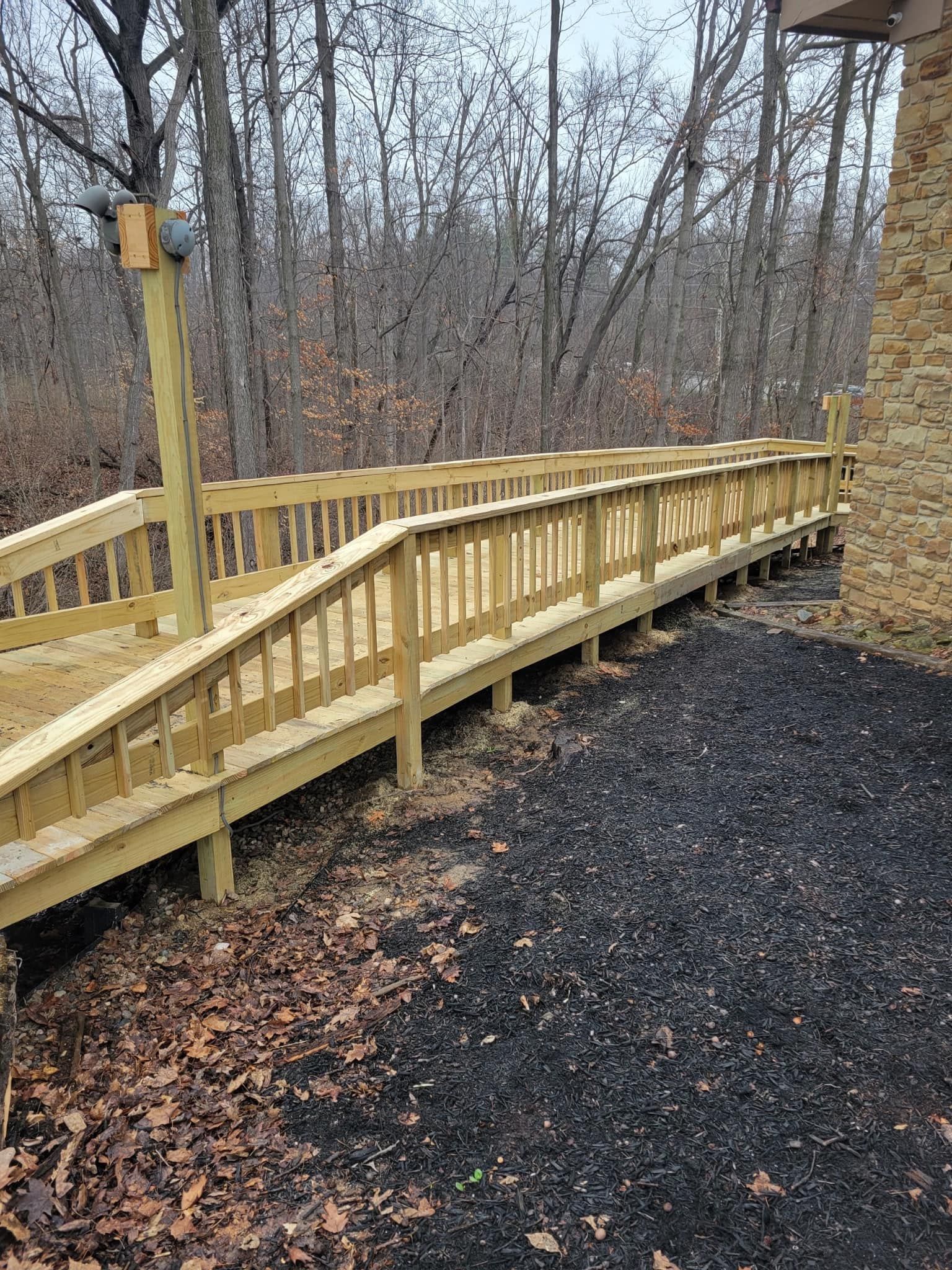 Wooden ramp with railings, built next to a building, surrounded by trees.
