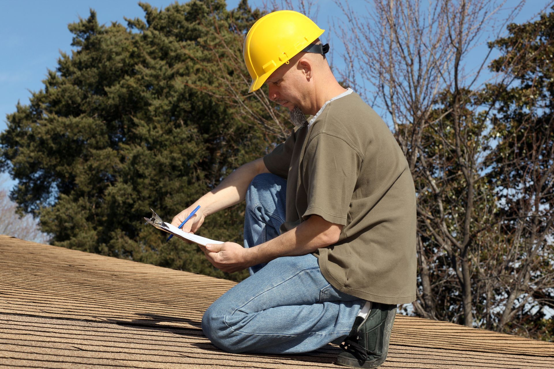 A man wearing a hard hat inspects a roof, performing a thorough home roofing inspection.