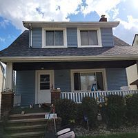 A blue house with a porch and stairs in front of it.