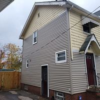 A house with a yellow siding and a red door.