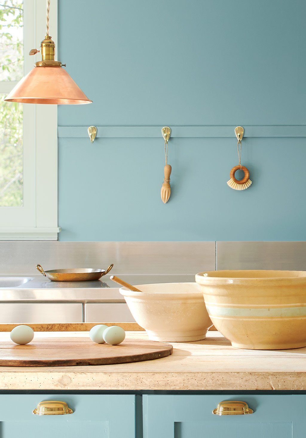 A kitchen with blue cabinets and bowls on the counter