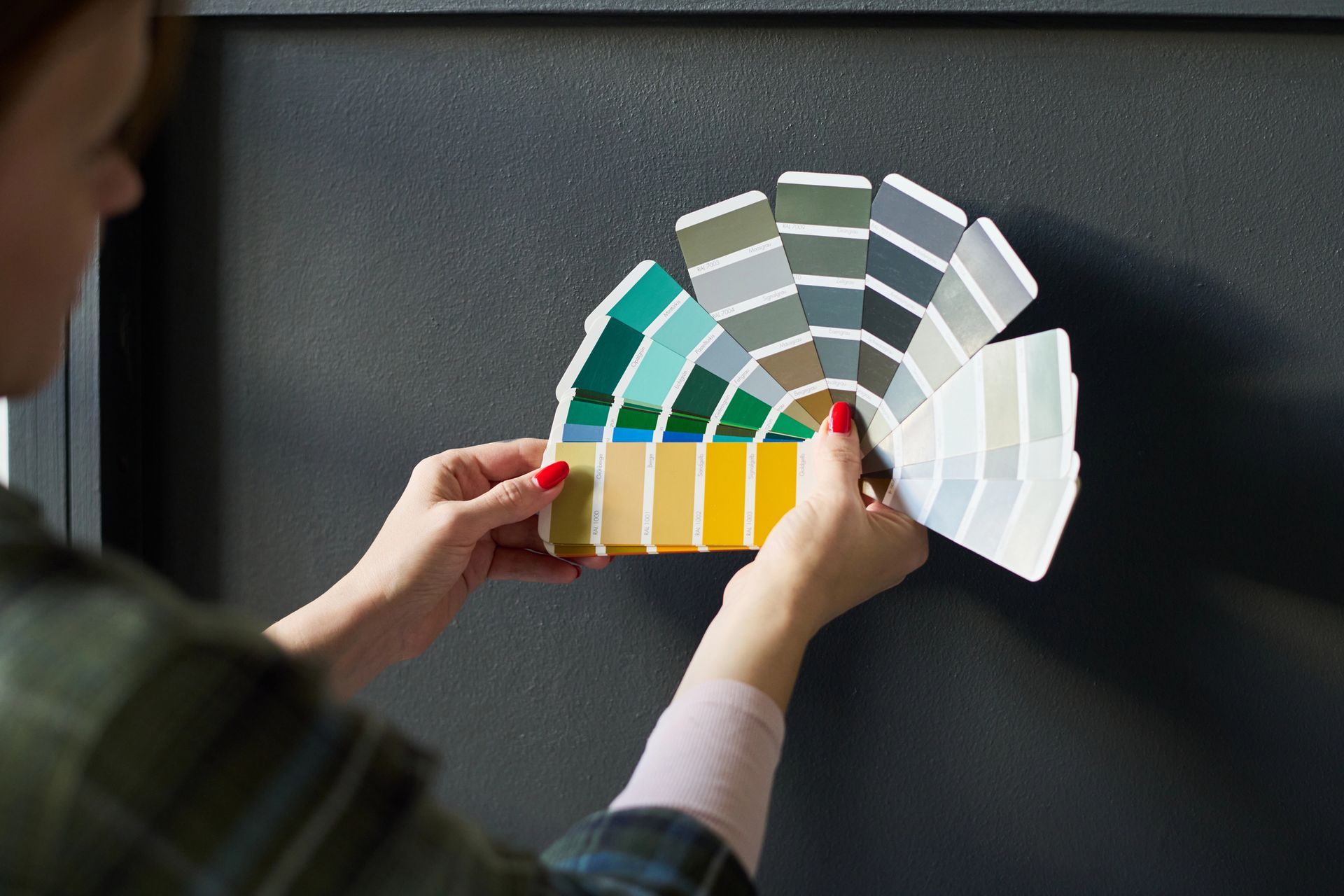A woman is holding a fan of paint samples in her hands.