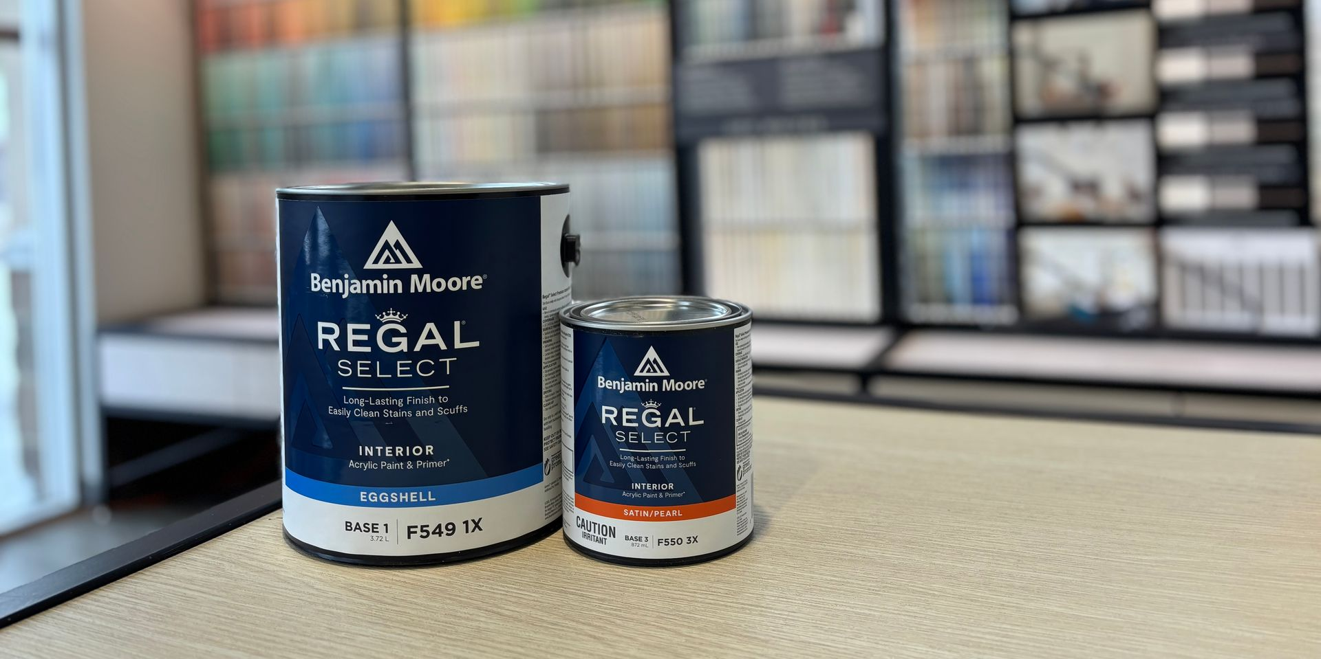 Three cans of paint and a swatch of paint are sitting on a table.