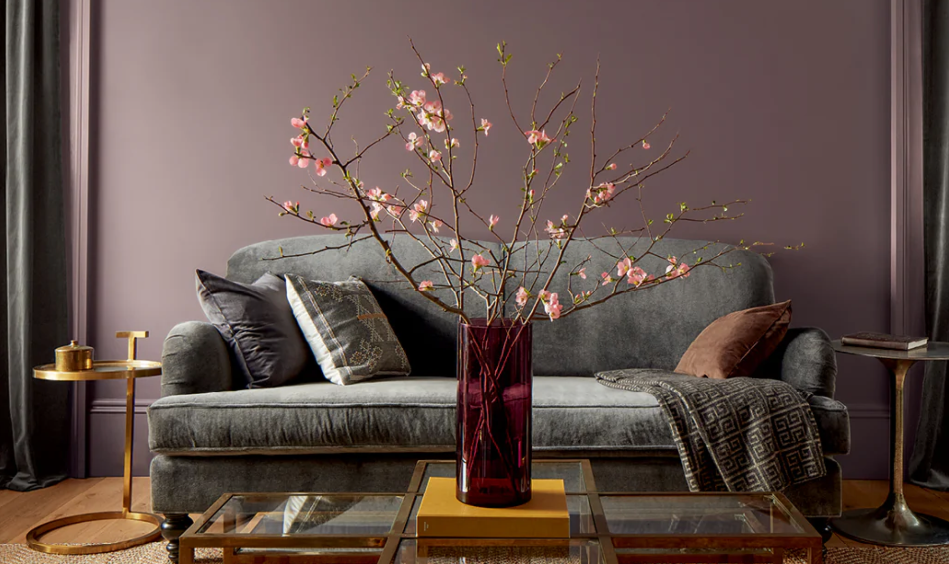 A living room with a couch and a vase of flowers on a coffee table.