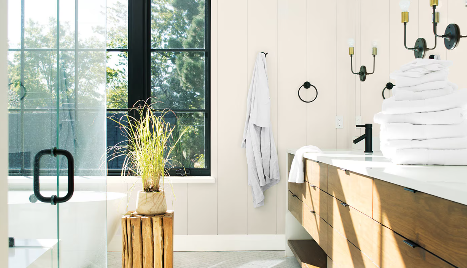 Bright bathroom with freestanding tub, wooden vanity, black fixtures, and a large window letting in sunlight