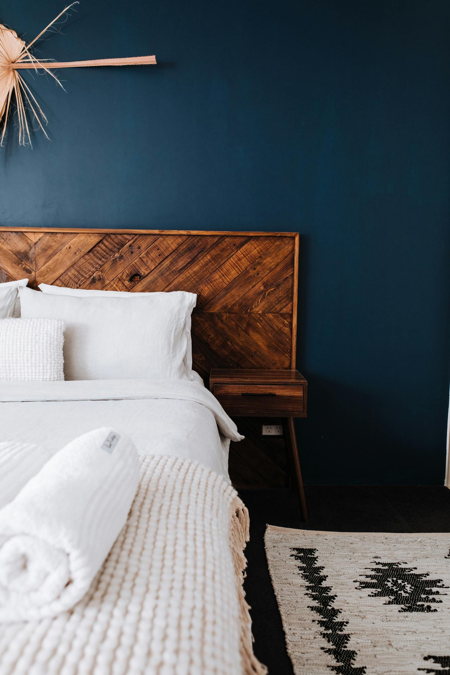 A bedroom with a bed , nightstand , rug and blue walls.