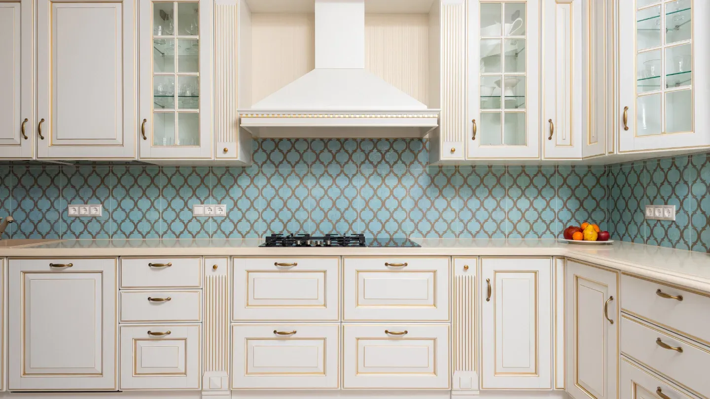 A kitchen with white cabinets and blue tiles on the wall.
