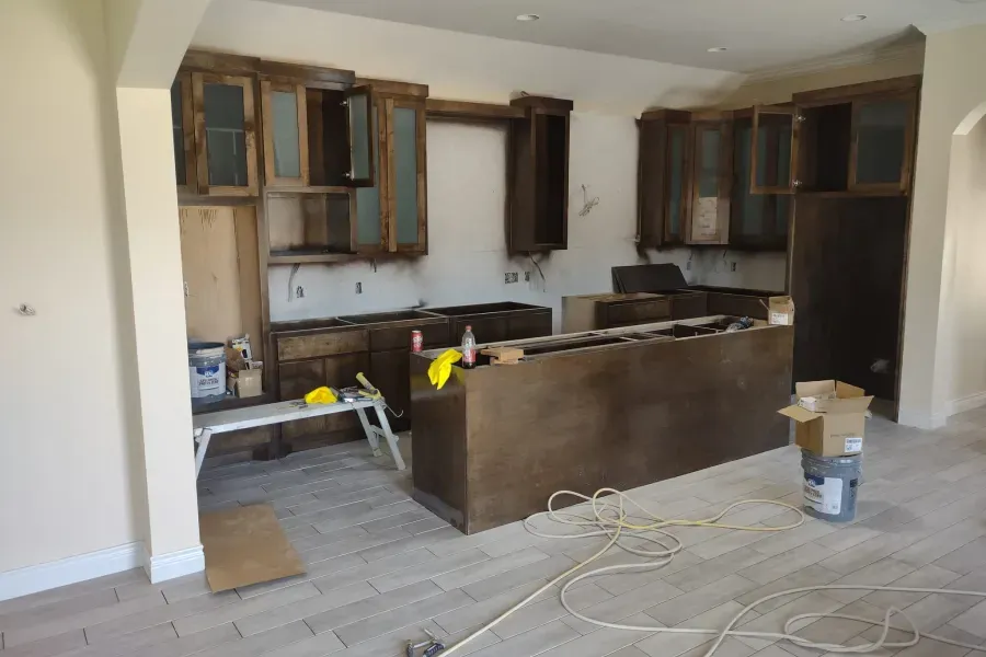 A kitchen is being remodeled with wooden cabinets and a large island.