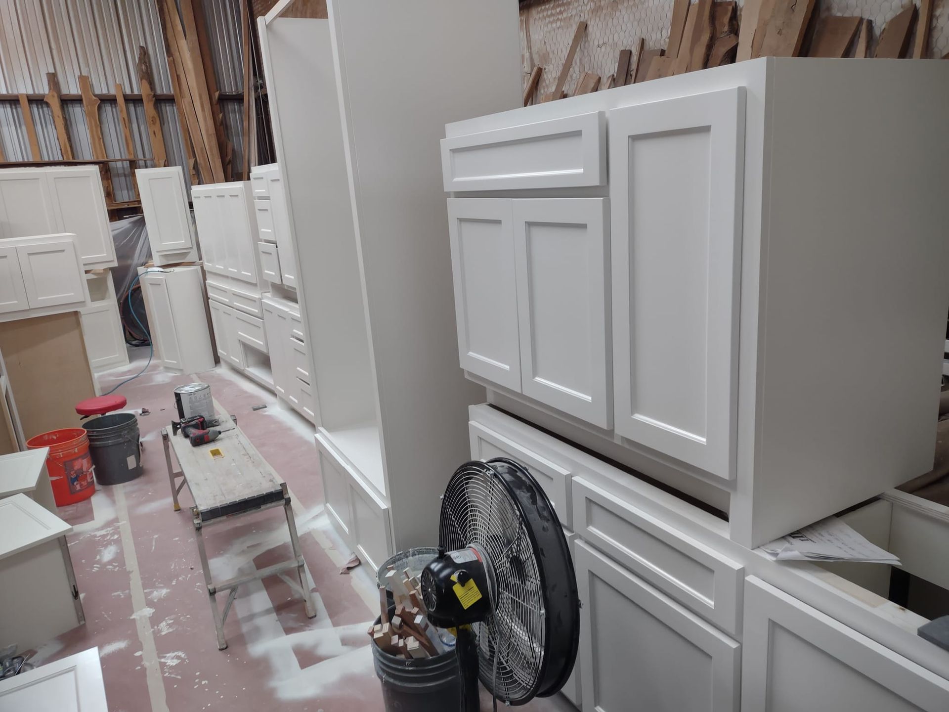 A warehouse filled with white cabinets and a fan.