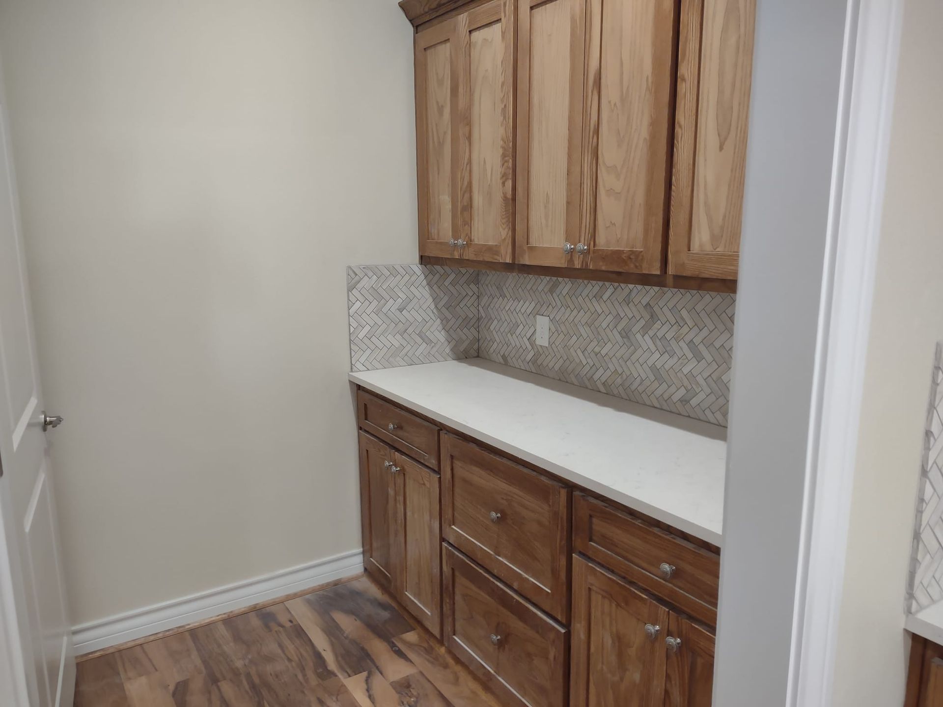 A kitchen with wooden cabinets and white counter tops.