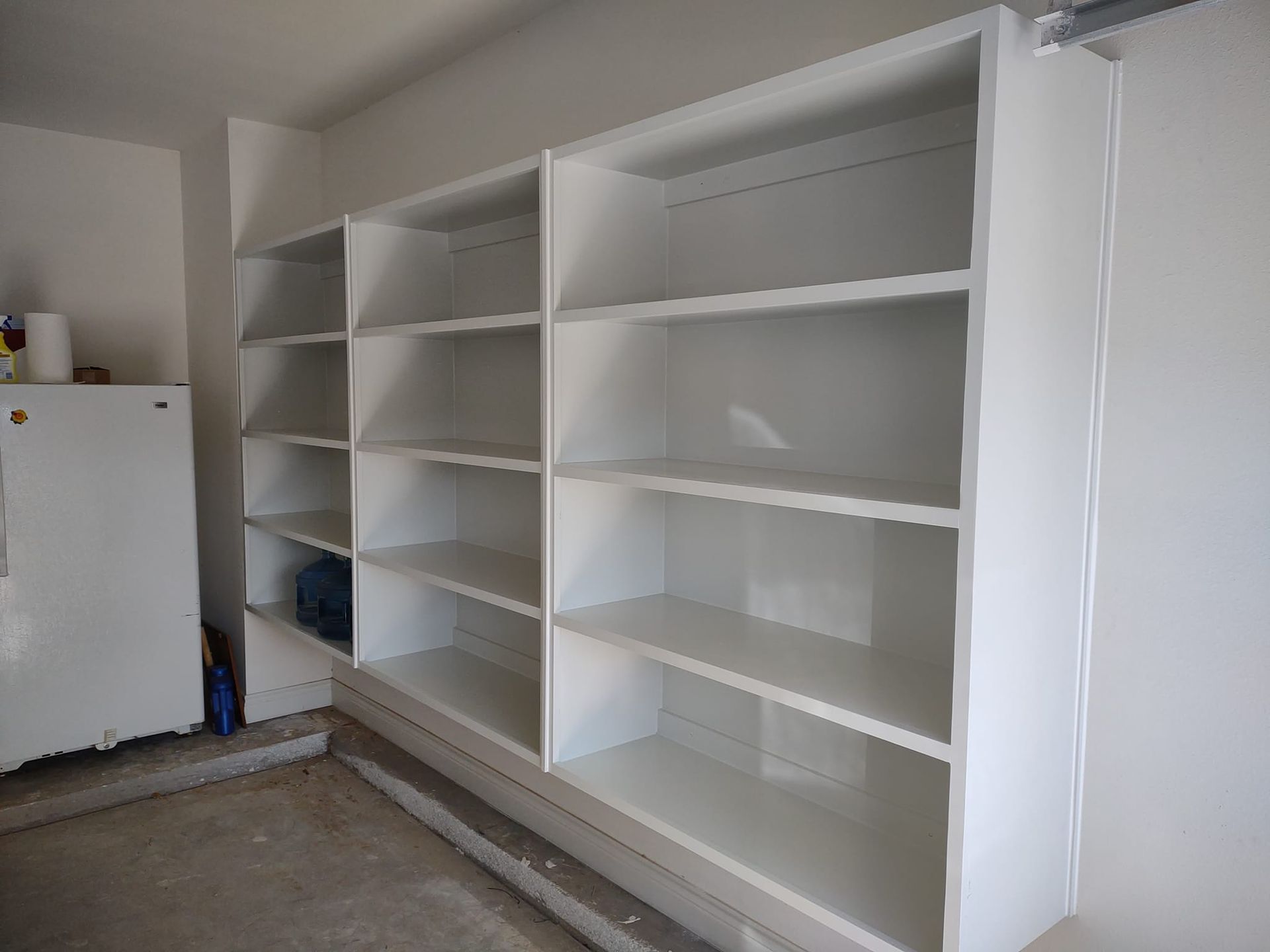 A room with a lot of shelves and a refrigerator