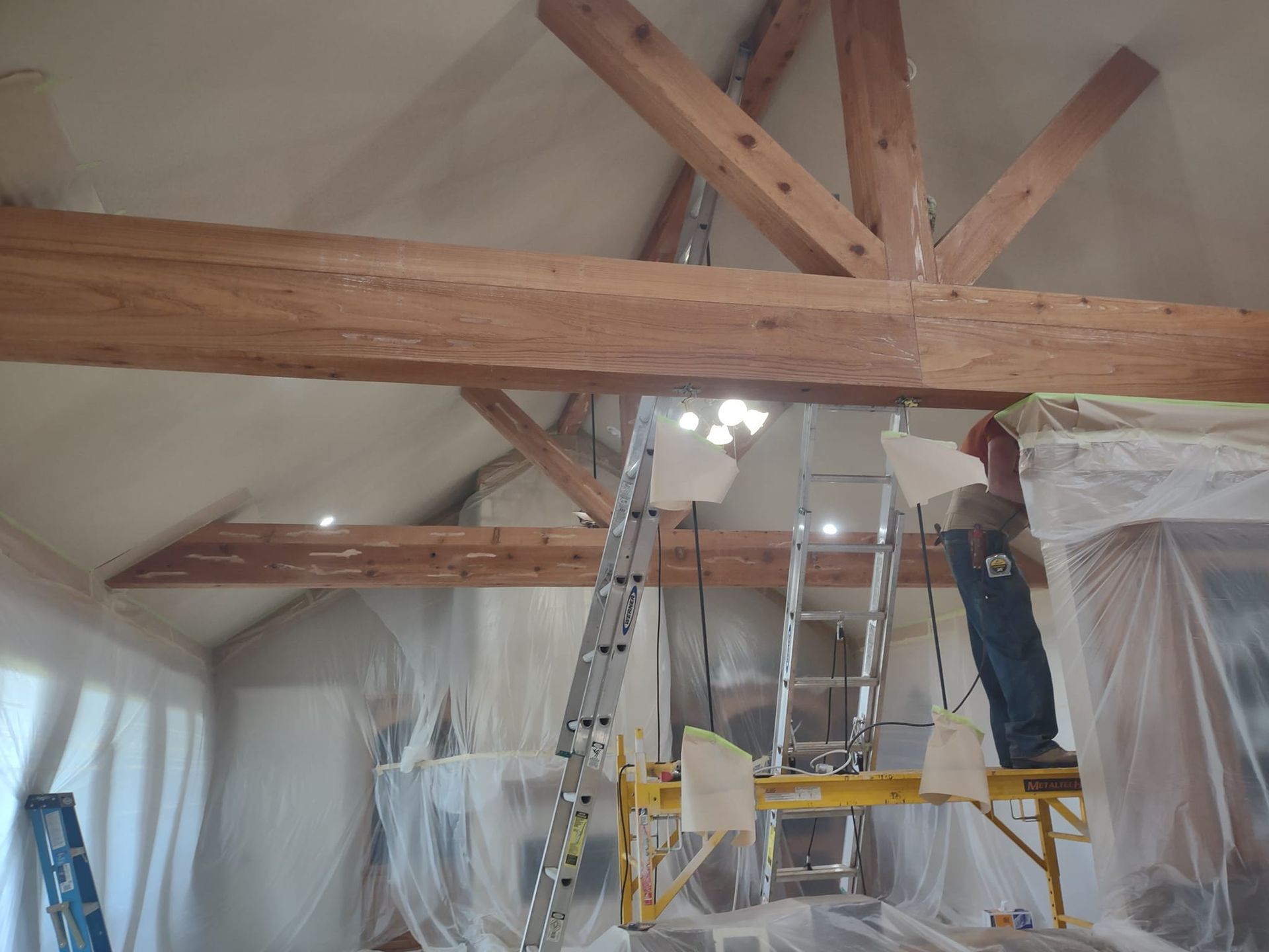 A man standing on a scaffolding in a room with a ladder