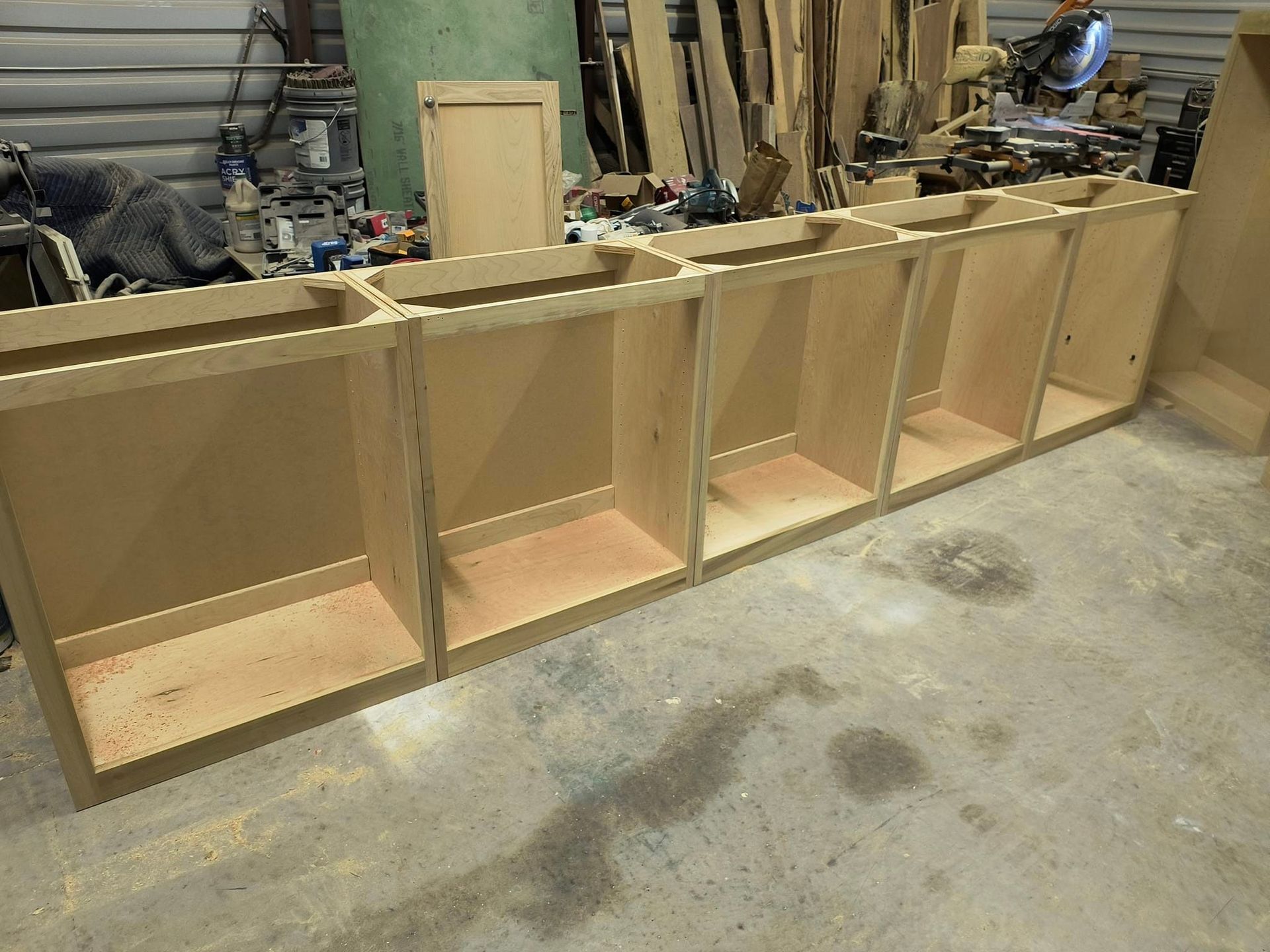 A row of wooden cabinets are sitting on a concrete floor.