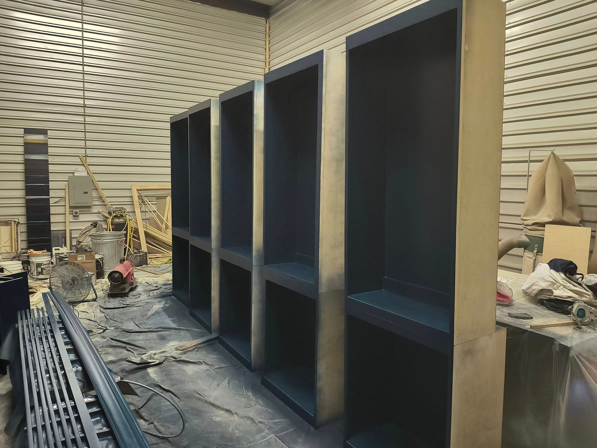 A row of shelves are being painted in a room.