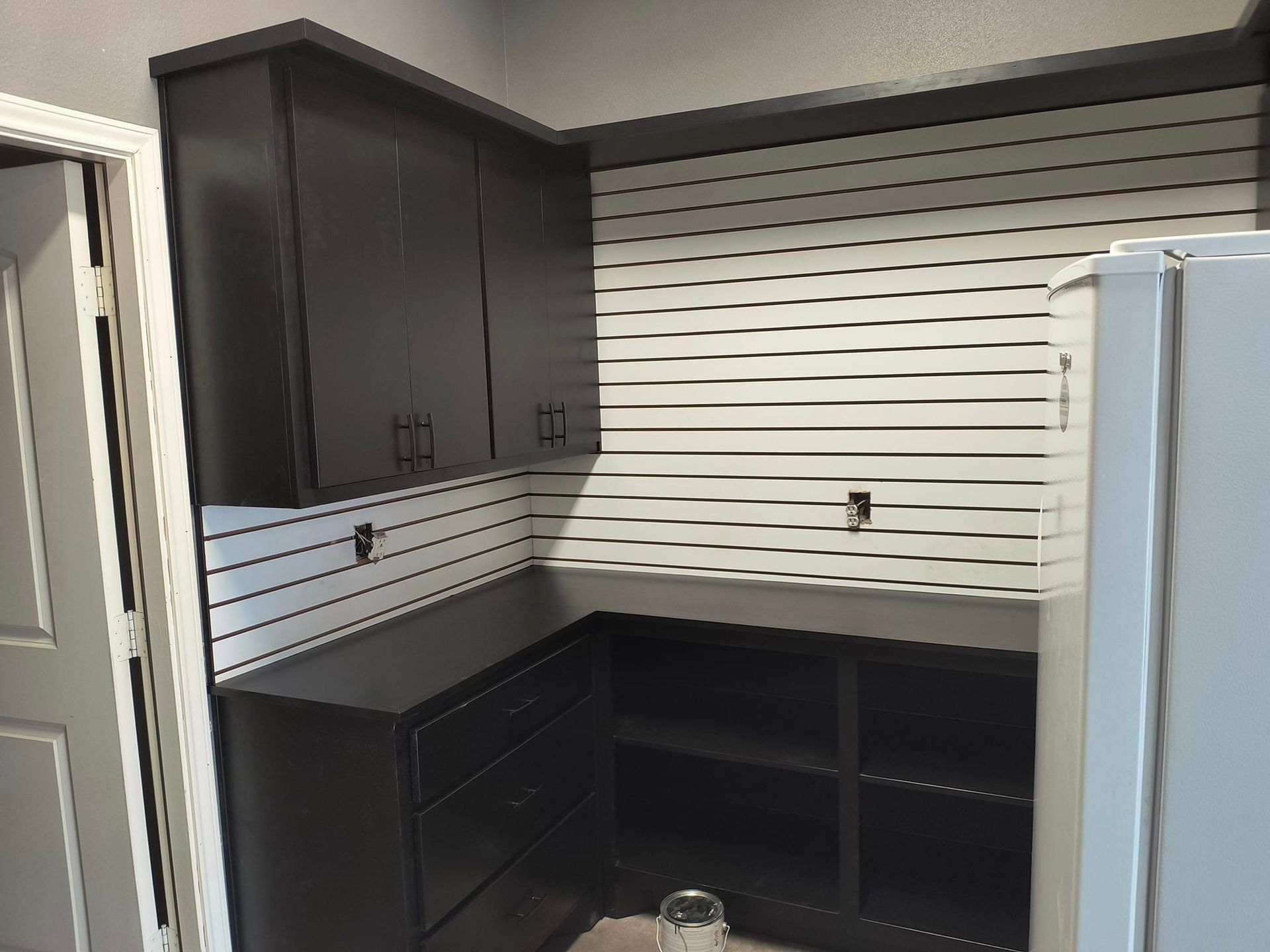 A kitchen with black cabinets and white stripes on the wall.